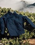 IPD jacket displayed outdoors on a bush with a scenic mountain background