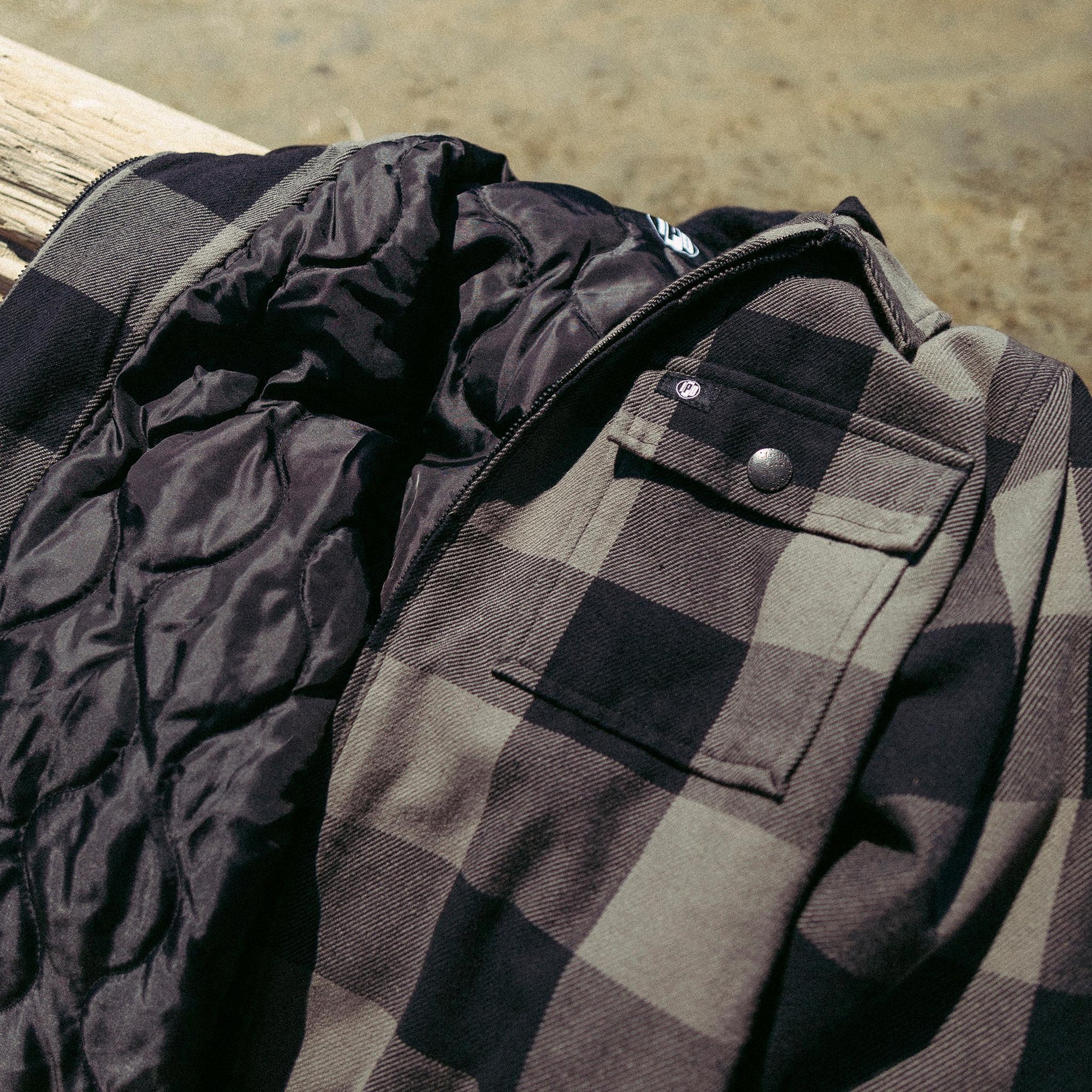 Front chest pocket view of fleece hooded olive flannel jacket with black stripes.
