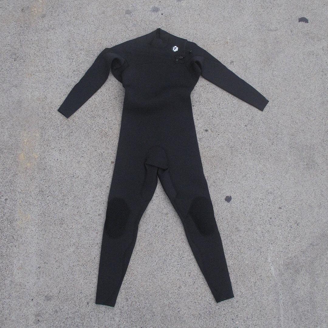front view of men's 3M front chest full body wetsuit while laying on ground. I P D circle logo on left shoulder with zipper running across chest from left to right side. 