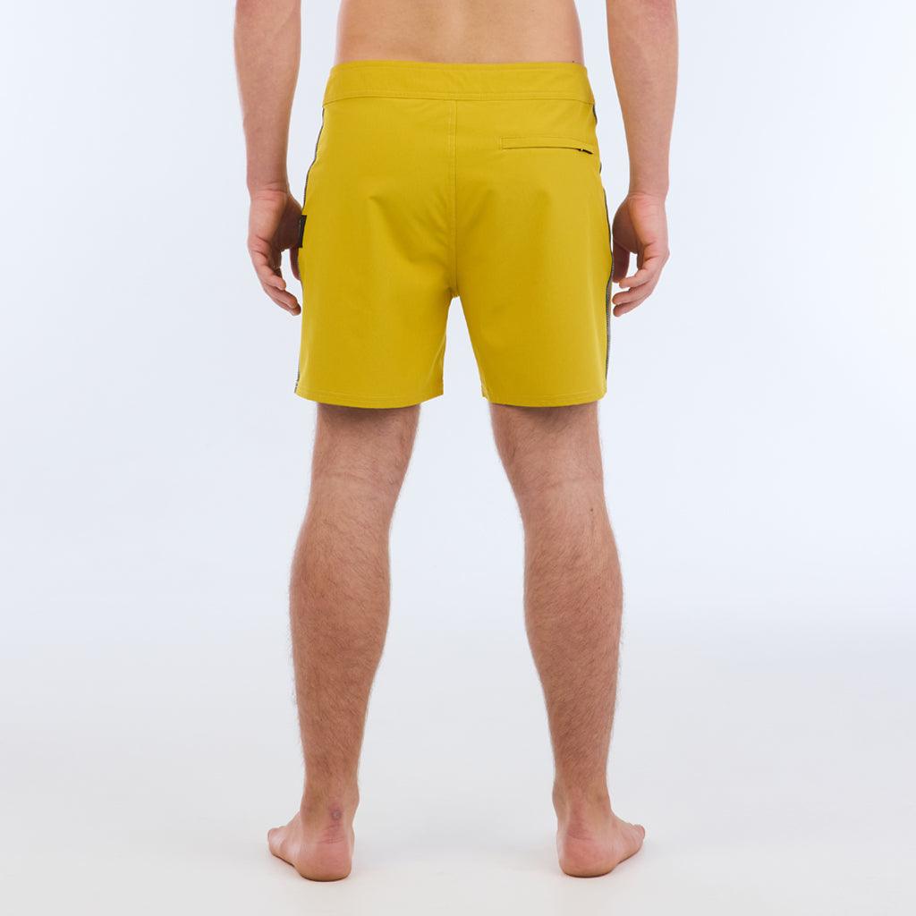 The B100 Chase boardshort features a 16” length and solid yellow coloring with a black and white striped side taping. It also has a waistband tie, side zipper pocket, and a black IPD logo patch halfway up the left leg taping. 
