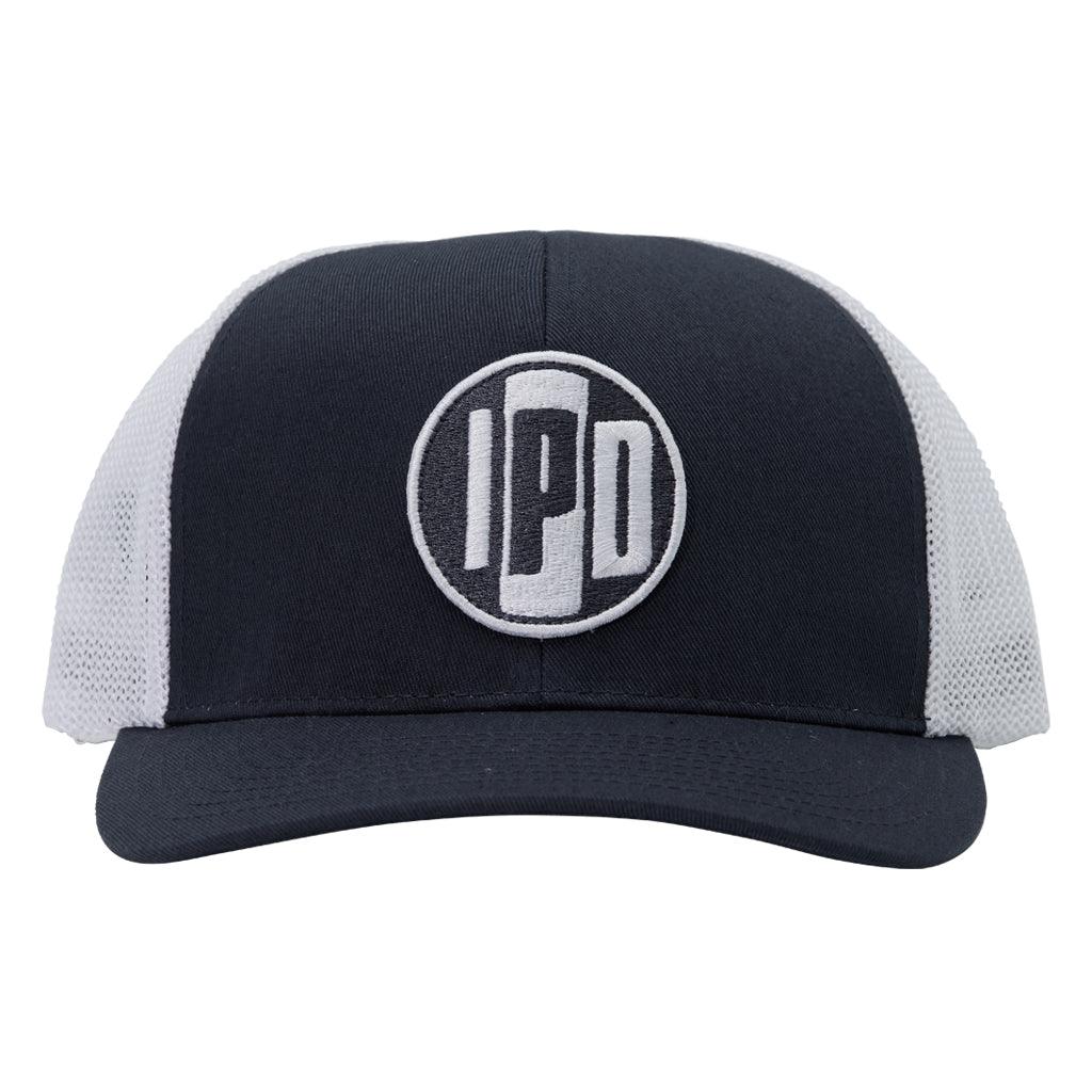 A structured trucker hat with white mesh on the back and a cotton twill white front. In the middle of the front is an embroidered IPD black and white patch logo. This hat has a curved brim and adjustable snap back. 